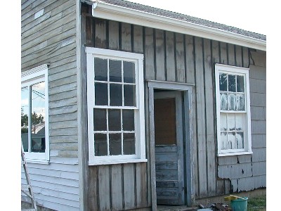 When the fiber board siding is removed, the original gray vertical barn board remains.