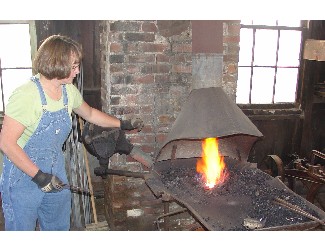 Lady Blacksmith fires up the forge for visitors in the fall of 2004.